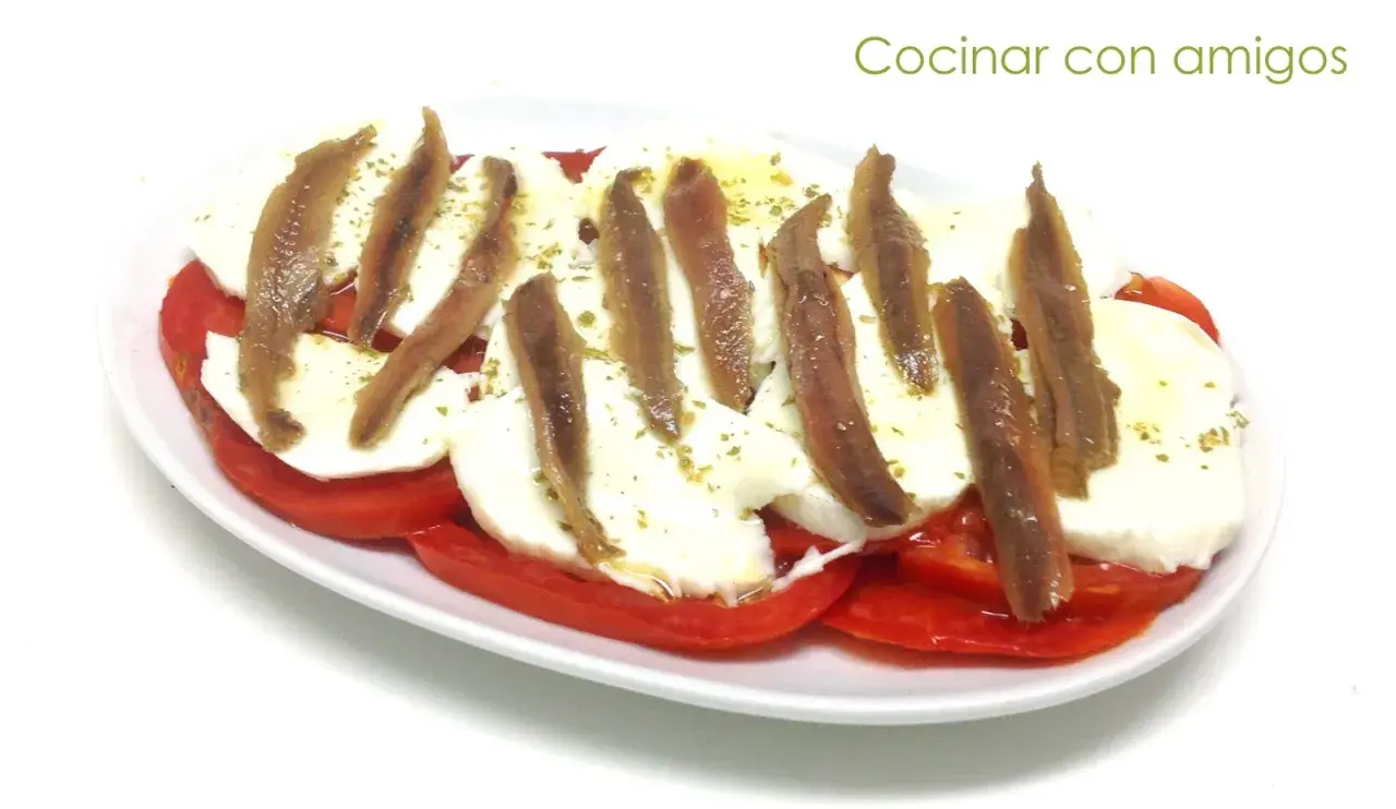 Ensalada caprese con anchoas, un toque salado que realza el sabor fresco de los tomates y la mozzarella. ¡Perfecta para compartir!
