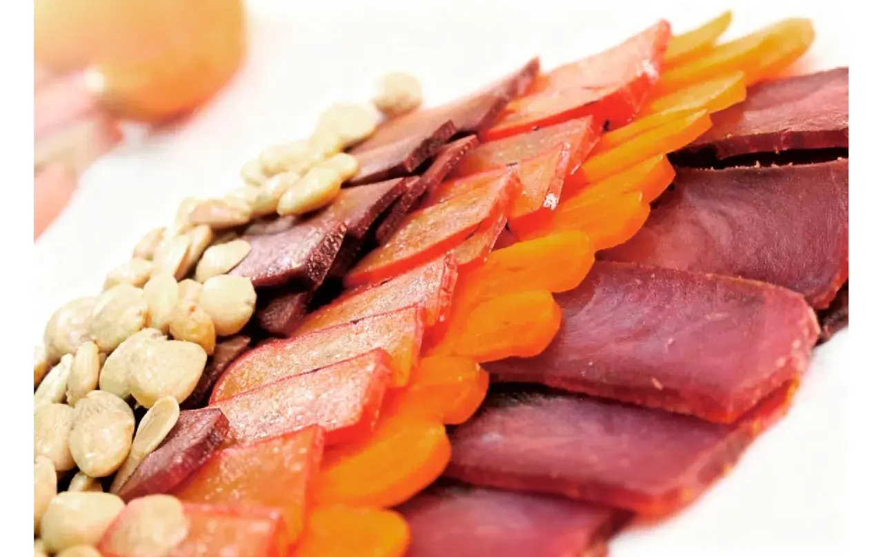 Finas lonchas de carne curada, como la mohama, junto a frutos secos y trozos de fruta deshidratada, crean un plato colorido y apetitoso.
