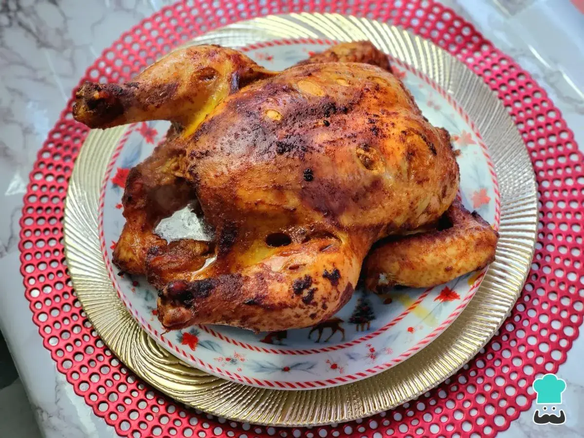 Un jugoso pollo a la brasa, dorado y crujiente, servido en un plato festivo con motivos navideños.
