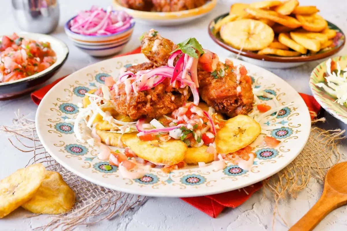 Pollo chuco crujiente con plátanos fritos, pico de gallo y cebolla morada encurtida. ¡Un festín de sabores!