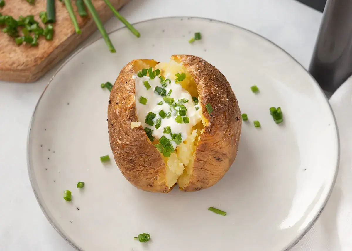 Patatas asadas crujientes rellenas de crema agria y cebollino fresco. Un plato sencillo y delicioso.
