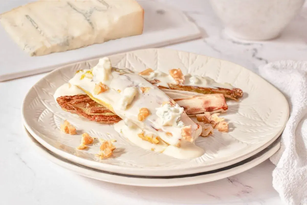 Endivias gratinadas con salsa cremosa, trozos de gorgonzola y nueces crujientes.