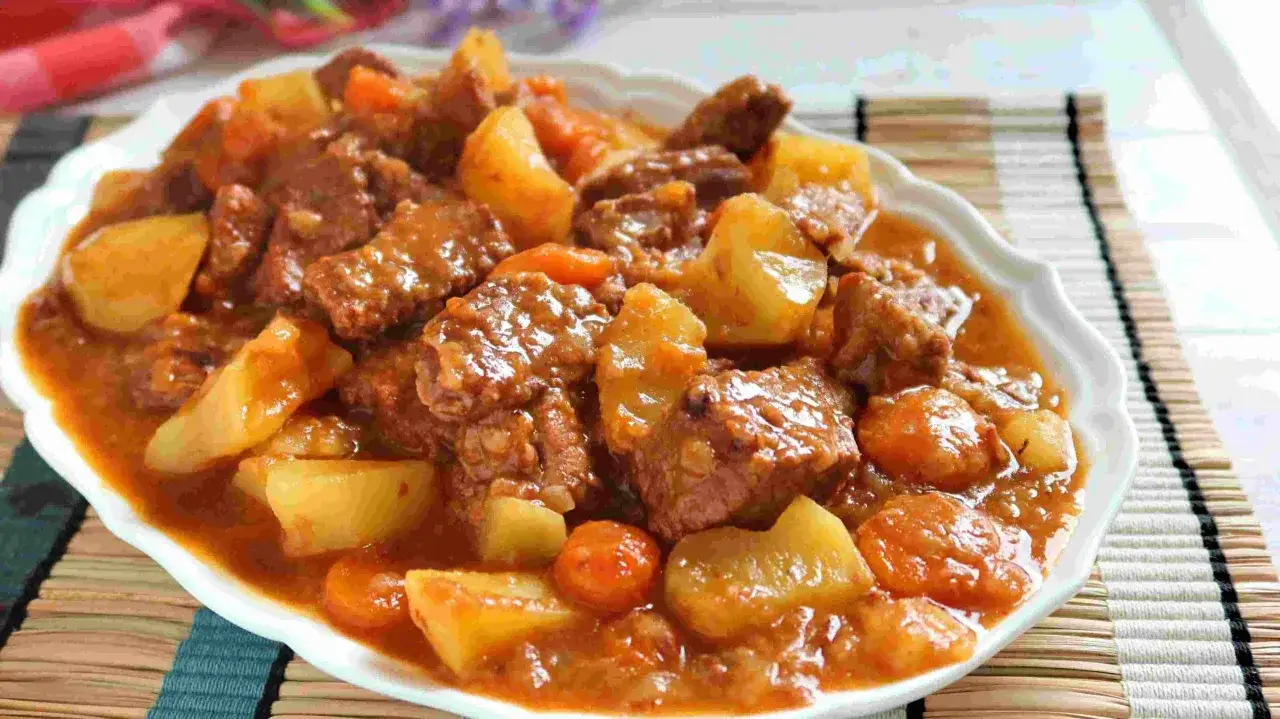Un delicioso estofado de ternera con patatas y zanahorias, servido en un plato blanco.