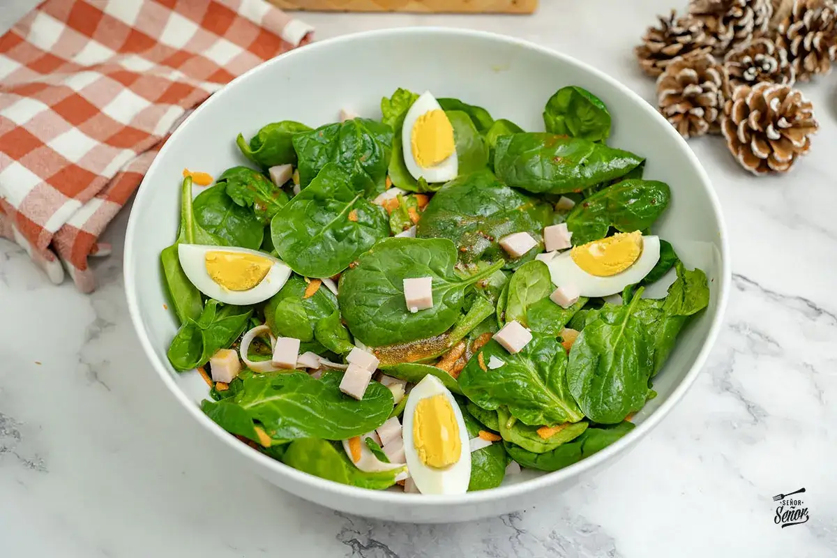 Deliciosa ensalada de espinacas con huevo duro, jam&oacute;n en cubos y zanahoria rallada, aderezada con una vinagreta.