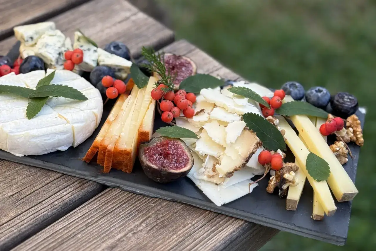 Deliciosas ideas para tablas de quesos: variedad de quesos, higos, ar&aacute;ndanos, nueces y bayas rojas sobre pizarra.