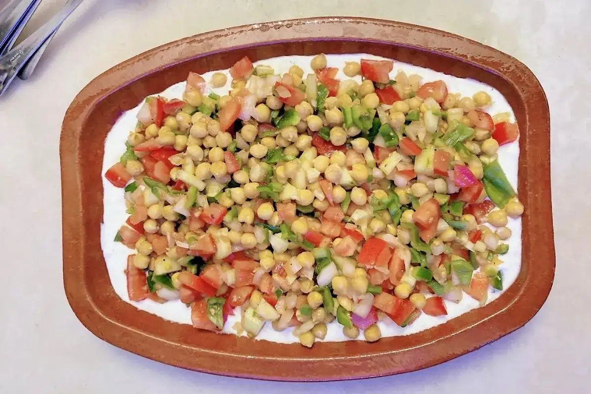 Ensalada de garbanzos con tomate y pimiento, una de las comidas frescas para el verano, servida en una cazuela de barro.