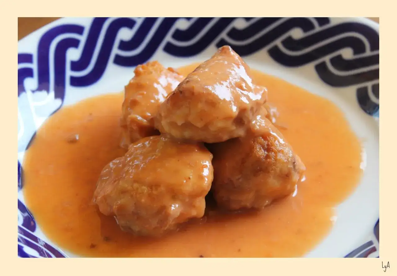 Albondigas de rape en salsa cremosa, servidas en un plato blanco con borde azul.