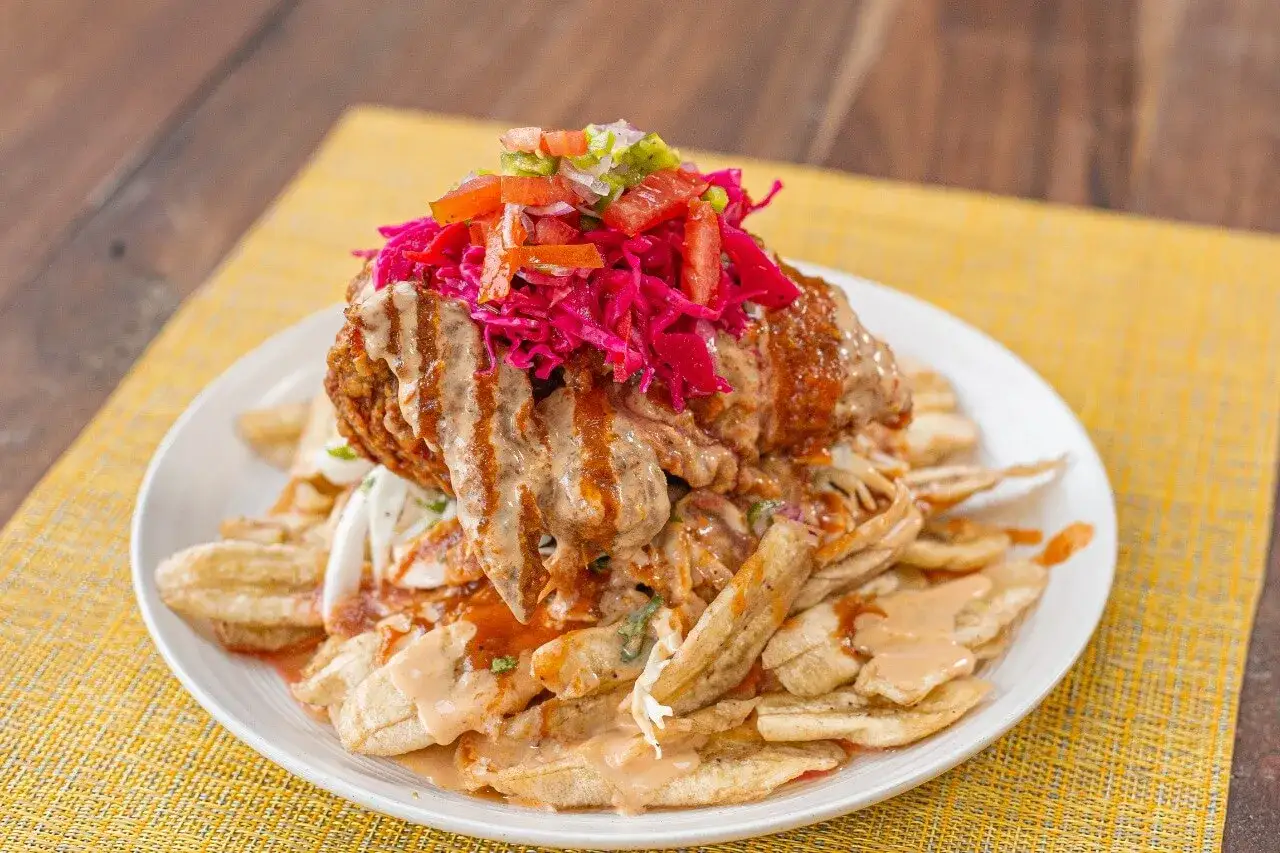 Pollo chuco con pl&aacute;tanos fritos, repollo morado y salsa cremosa. Un plato abundante y delicioso.
