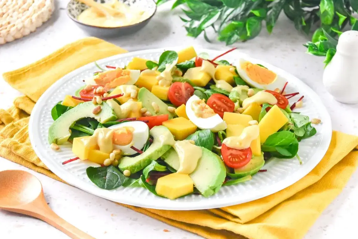 Deliciosa ensalada de mango con aguacate, huevo duro, tomates cherry y pi&ntilde;ones, aderezada con una cremosa salsa.