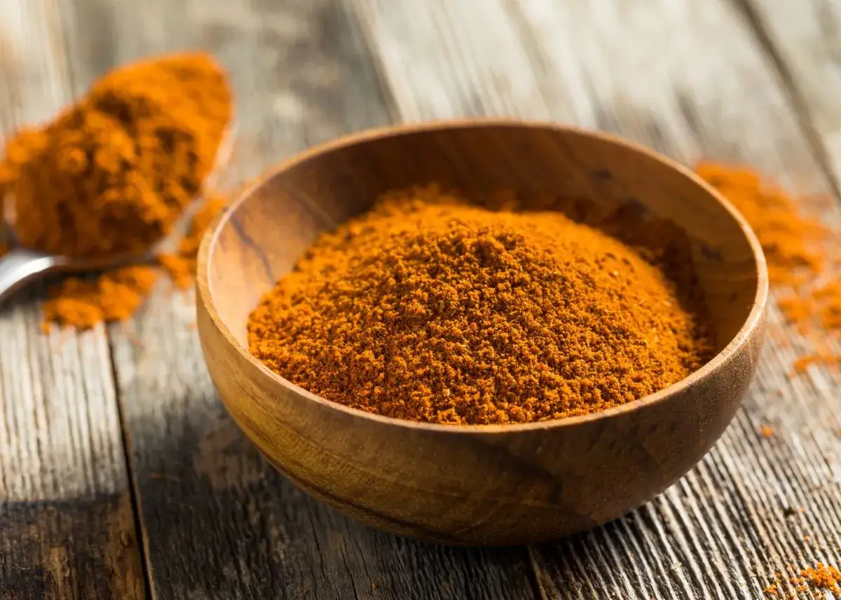Especias anaranjadas en un cuenco de madera, listas para aprender como hacer ras el hanout.