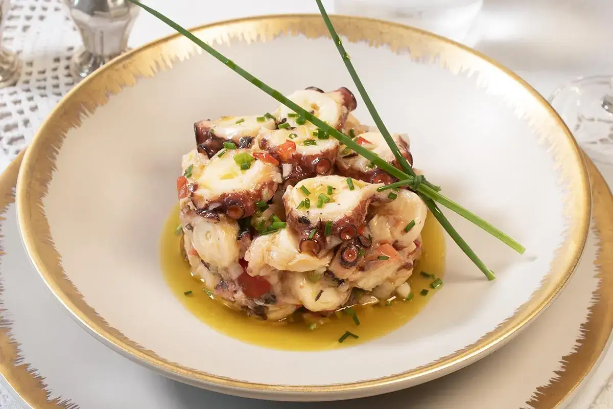 Delicioso salpicón de pulpo, con trozos de pulpo tierno, pimientos y cebolla, aderezado con aceite de oliva y hierbas frescas.