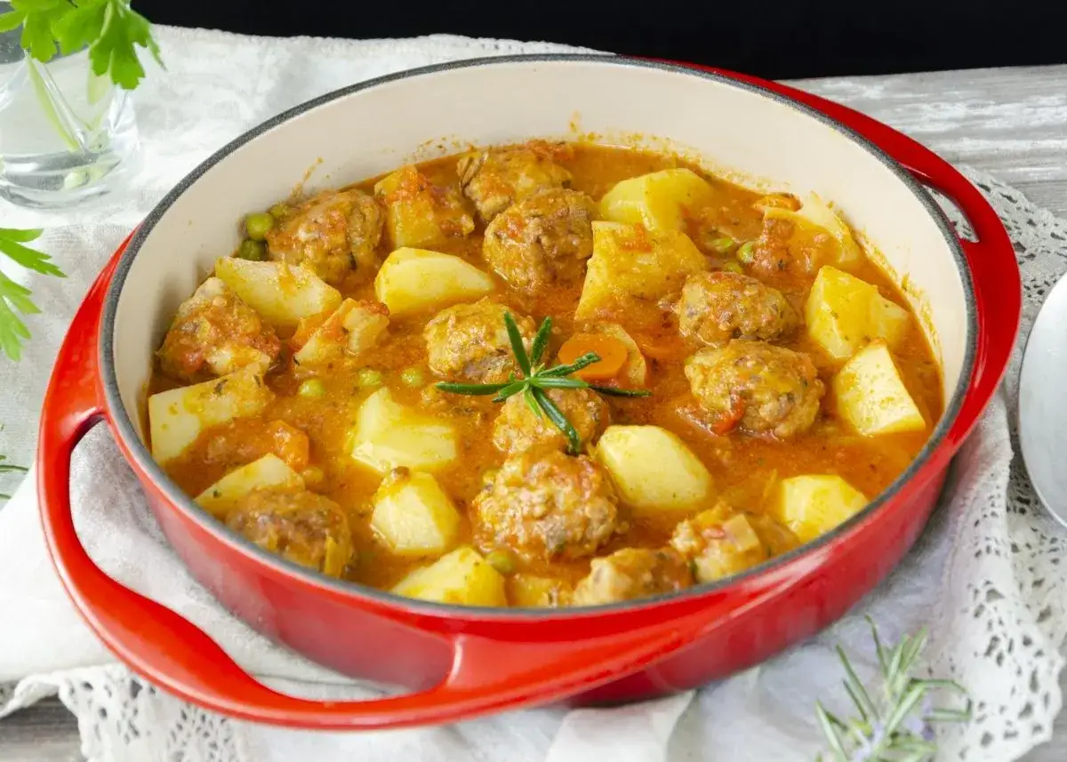 Plato de alb&oacute;ndigas caseras en salsa con patatas y guisantes. Una deliciosa receta de alb&oacute;ndigas para disfrutar en familia.