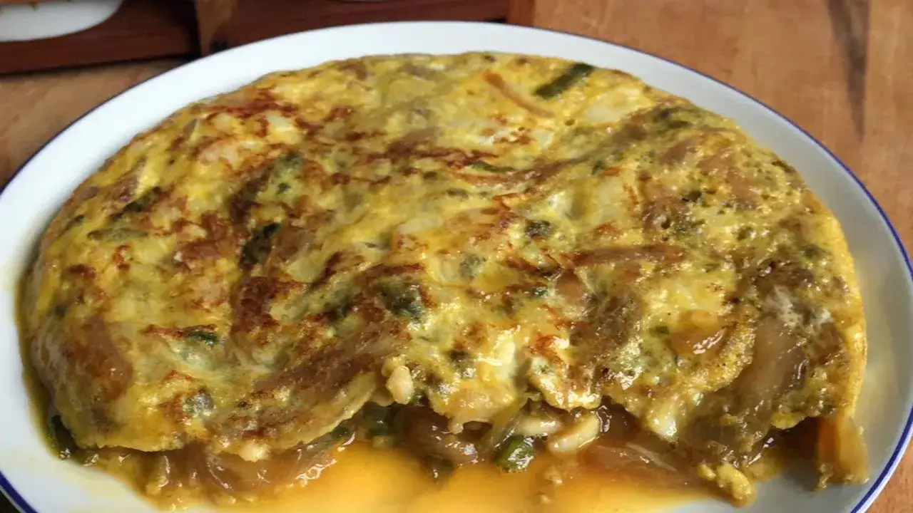 Tortilla de bacalao vasca jugosa y dorada, con trozos de bacalao y cebolla caramelizada.