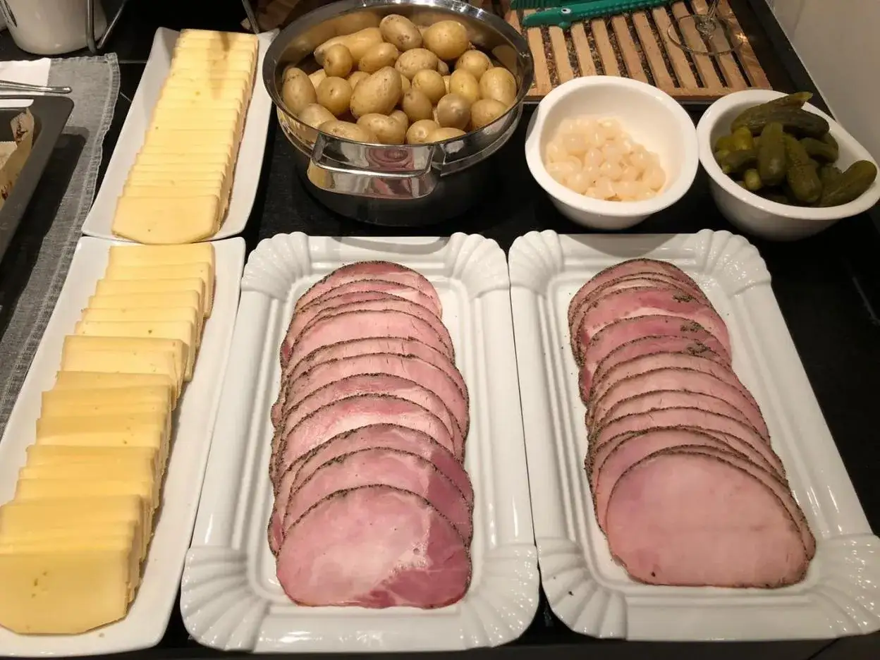 Queso en lonchas, patatas, pepinillos y embutido para preparar deliciosas recetas raclette.