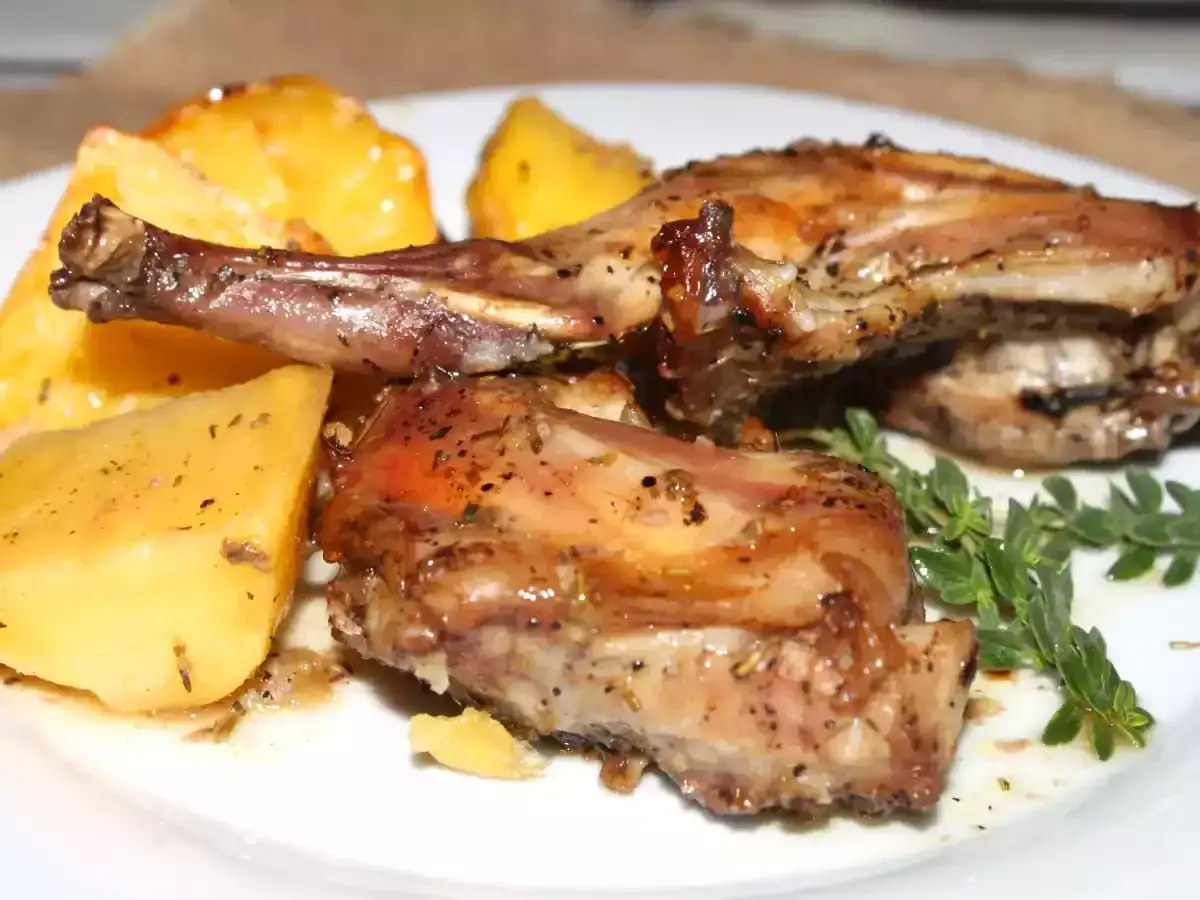 Delicioso conejo al horno con patatas asadas y hierbas frescas. Un plato casero que huele a tradici&oacute;n.
