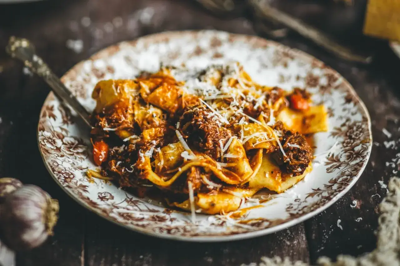 Un plato de pasta con ragú, cubierto de queso rallado. El ragú, una salsa de carne cocida a fuego lento, es el alma de este delicioso plato.