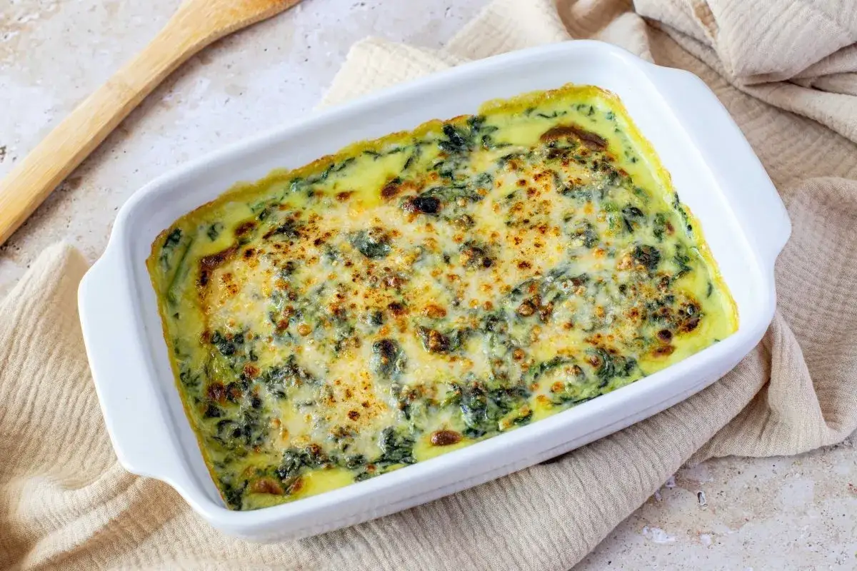 Un cremoso y dorado plato de espinacas a la crema, reci&eacute;n salido del horno, listo para ser servido.