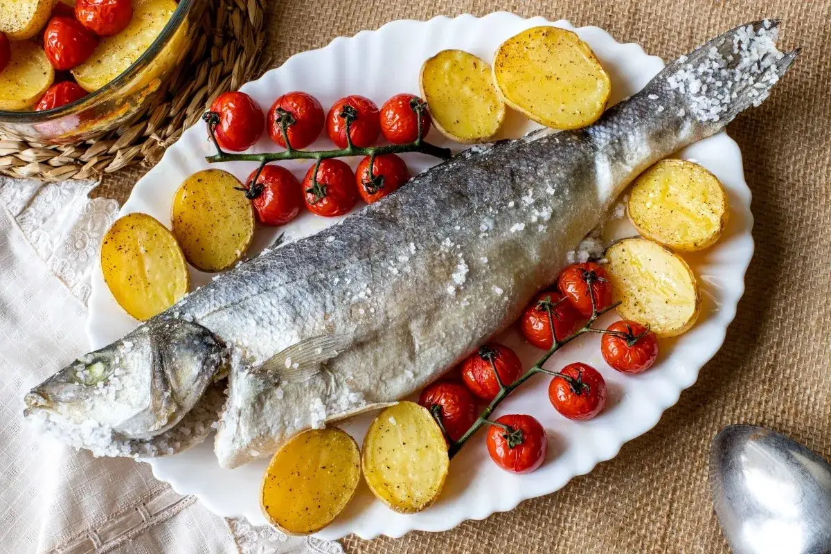 Lubina a la sal entera, horneada con patatas y tomates cherry. Un plato principal delicioso y saludable.