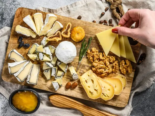 Tabla de quesos variados, incluyendo queso brie con que se acompaña de miel, higos secos, nueces y almendras.